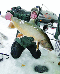 image of ice fisherman holding giant Lake Trout on ice